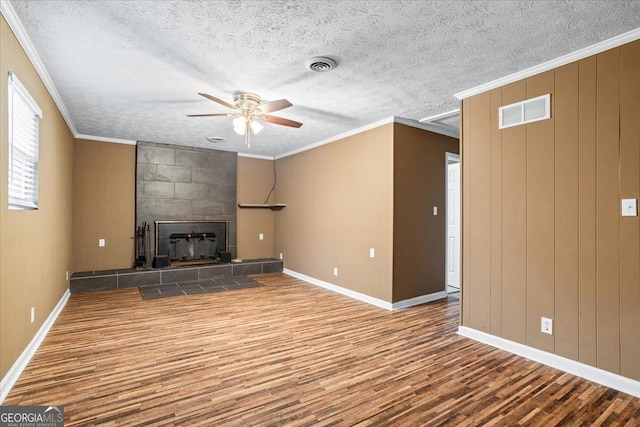 unfurnished living room with crown molding, wood-type flooring, a textured ceiling, ceiling fan, and a fireplace