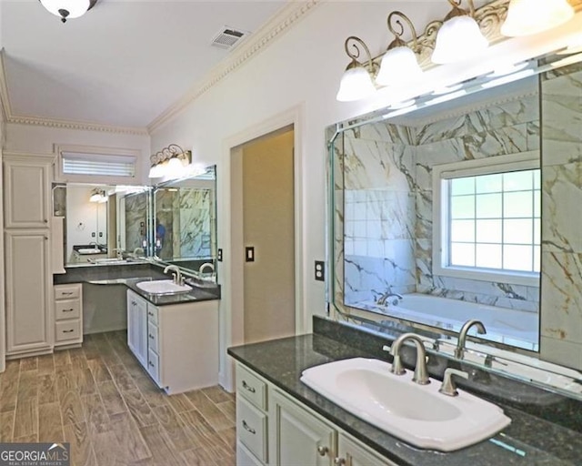 bathroom with vanity, ornamental molding, and a tub