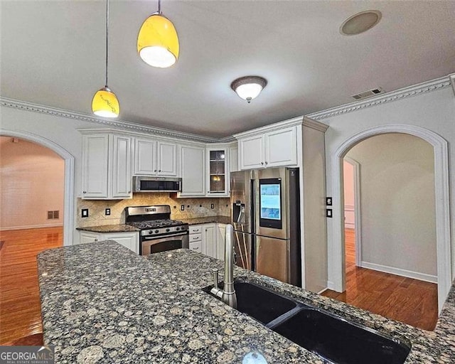 kitchen featuring pendant lighting, dark stone countertops, white cabinets, and appliances with stainless steel finishes