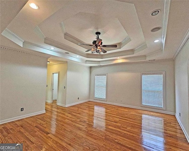 empty room with crown molding, light hardwood / wood-style flooring, a raised ceiling, and ceiling fan