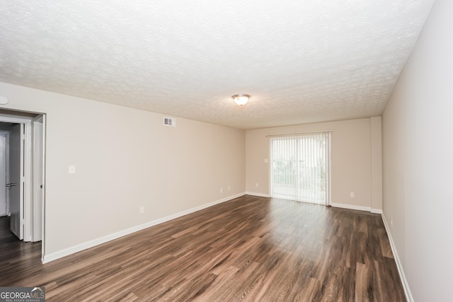 empty room featuring dark wood-type flooring and a textured ceiling