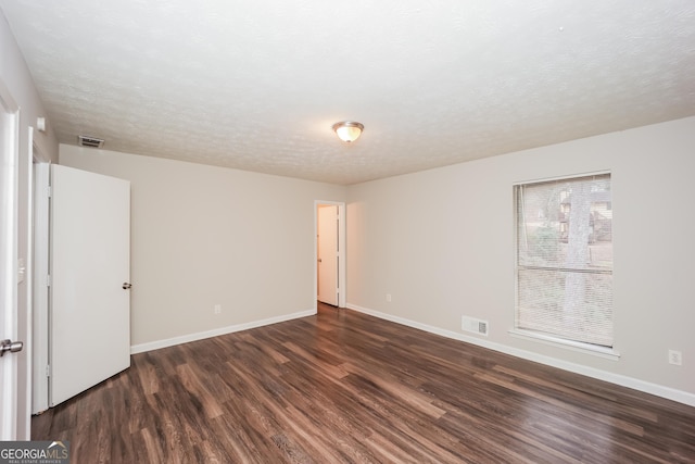 spare room featuring dark wood-type flooring and a textured ceiling