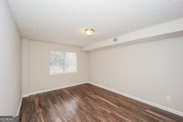 unfurnished room with dark hardwood / wood-style flooring and a textured ceiling