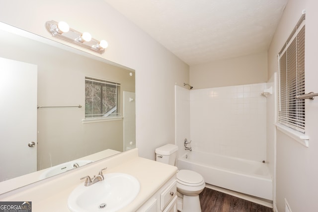 full bathroom featuring hardwood / wood-style flooring, tiled shower / bath combo, vanity, a textured ceiling, and toilet