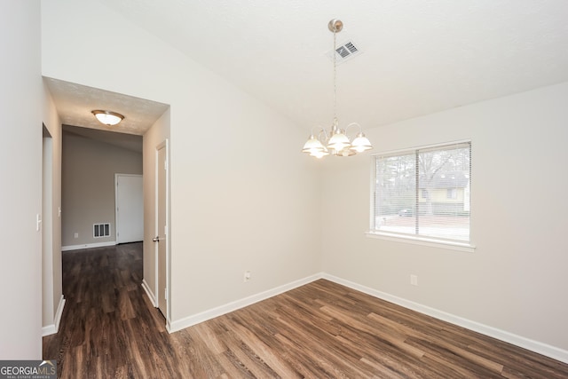 empty room with dark wood-type flooring, vaulted ceiling, and a notable chandelier