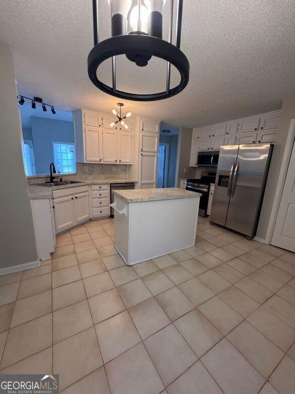 kitchen with sink, white cabinetry, a textured ceiling, a kitchen island, and stainless steel appliances