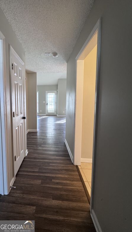 corridor featuring dark hardwood / wood-style flooring and a textured ceiling