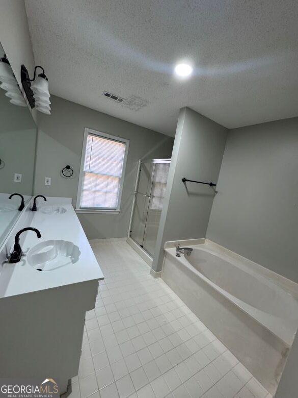 bathroom featuring vanity, shower with separate bathtub, and a textured ceiling