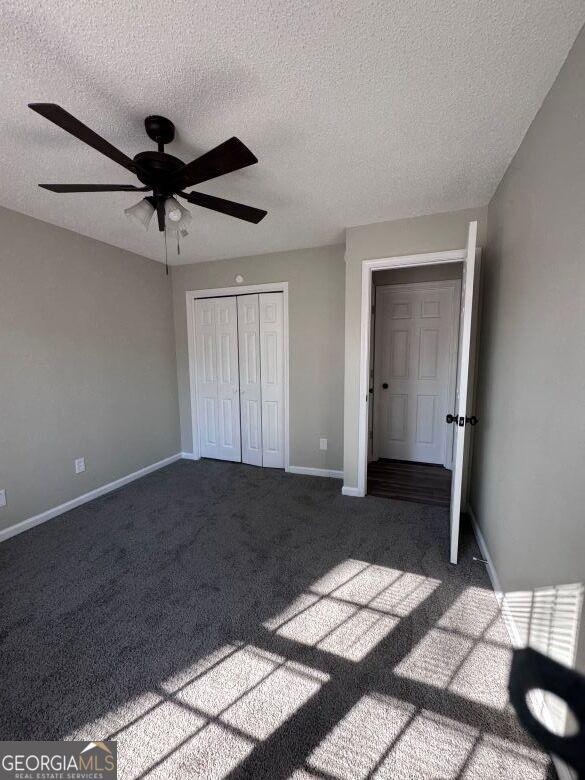 unfurnished bedroom featuring carpet floors, a textured ceiling, ceiling fan, and a closet