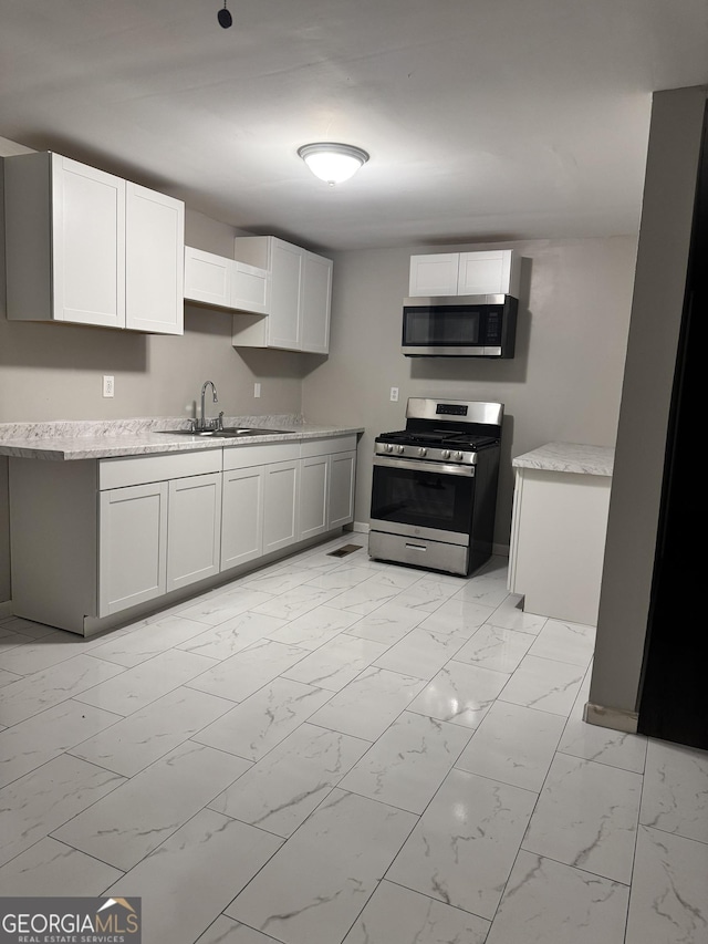 kitchen with appliances with stainless steel finishes, sink, and white cabinets