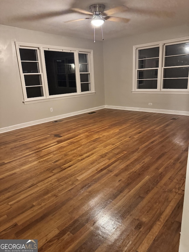 empty room featuring dark wood-type flooring and ceiling fan