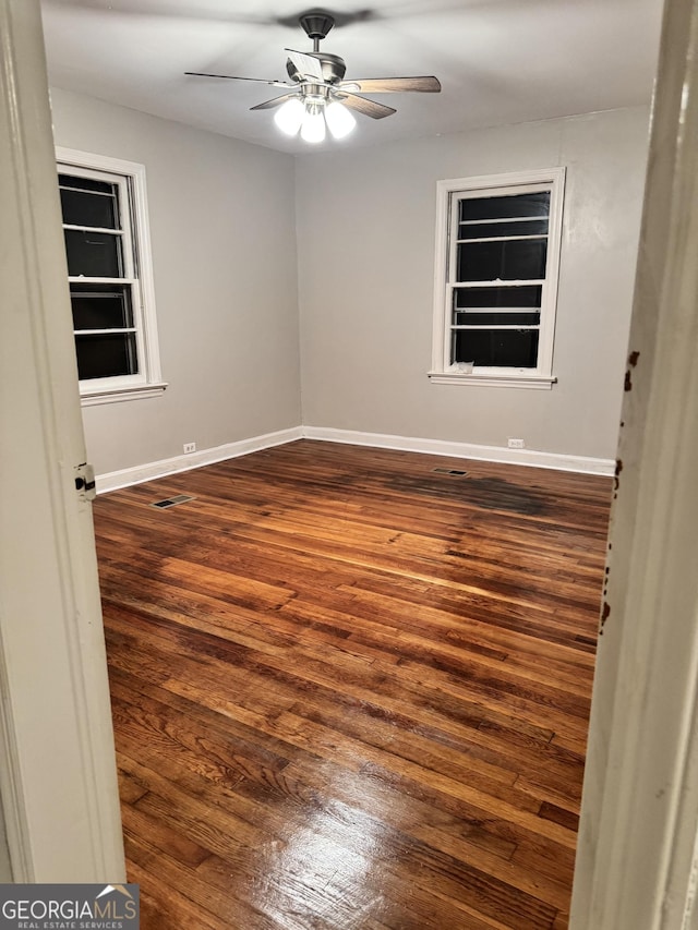 spare room with dark wood-type flooring and ceiling fan