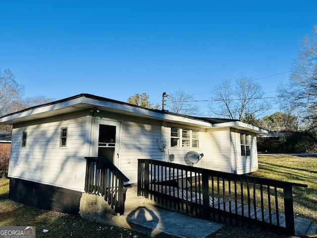 back of house featuring a deck and a lawn