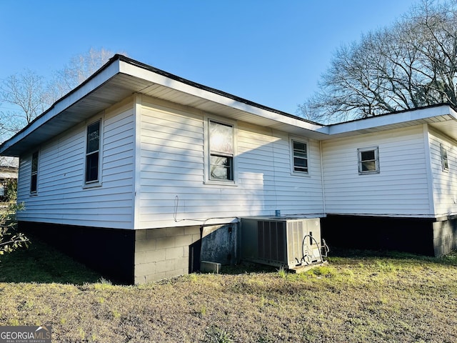 view of side of property featuring central AC unit and a lawn