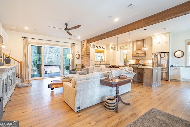 living room with beamed ceiling, ceiling fan, and light hardwood / wood-style flooring