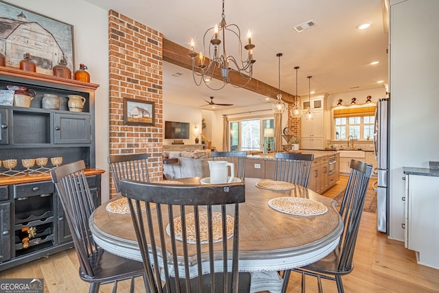 dining area with sink, ceiling fan with notable chandelier, and light wood-type flooring