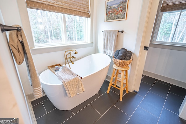 bathroom with a wealth of natural light, a washtub, and tile patterned floors