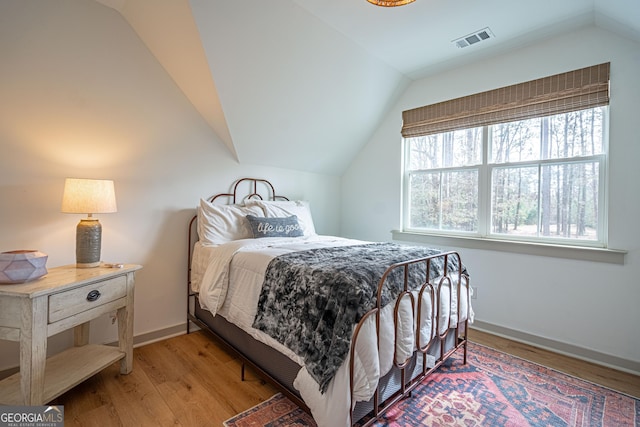 bedroom featuring lofted ceiling and light hardwood / wood-style floors