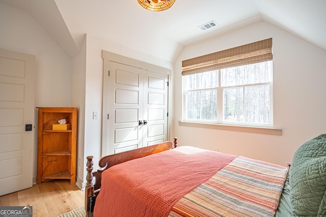 bedroom with wood-type flooring, vaulted ceiling, and a closet