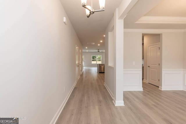 hallway with light wood finished floors, visible vents, wainscoting, an inviting chandelier, and a decorative wall