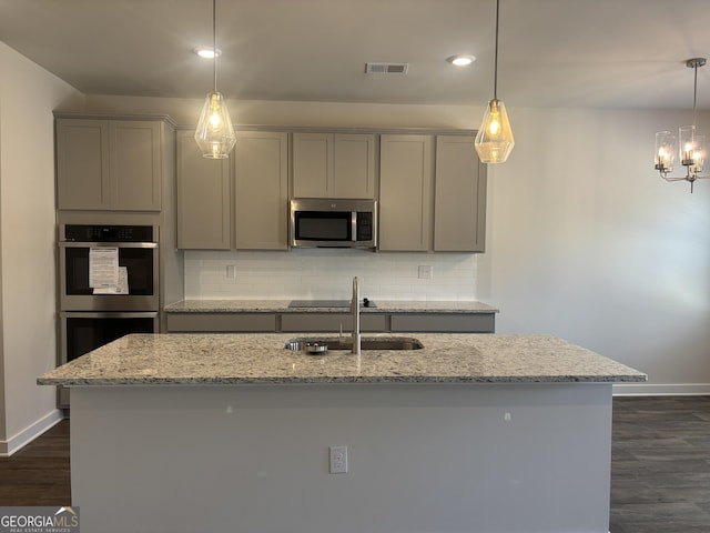 kitchen featuring light stone countertops, appliances with stainless steel finishes, sink, and decorative light fixtures