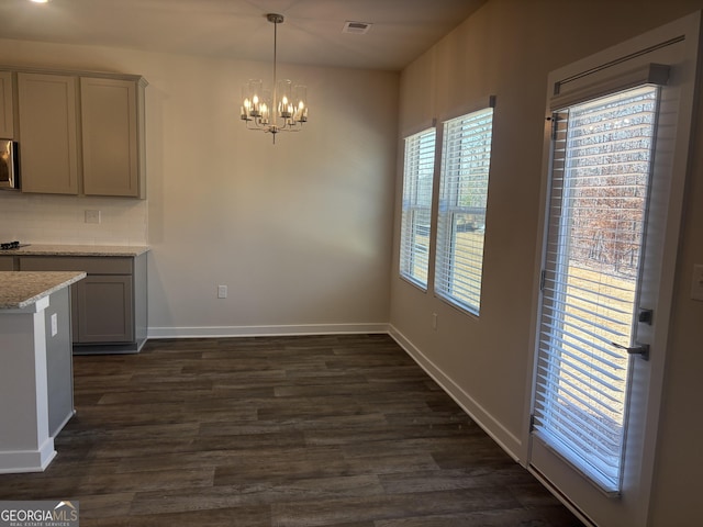 kitchen with gray cabinets, pendant lighting, dark hardwood / wood-style flooring, a notable chandelier, and light stone countertops