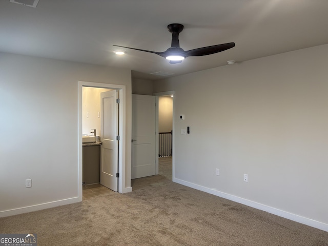 unfurnished bedroom featuring light colored carpet, ceiling fan, and ensuite bathroom