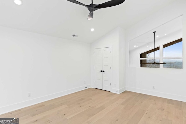 spare room with vaulted ceiling, ceiling fan, and light wood-type flooring