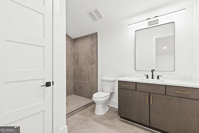 bathroom with tile patterned floors, vanity, toilet, and a tile shower