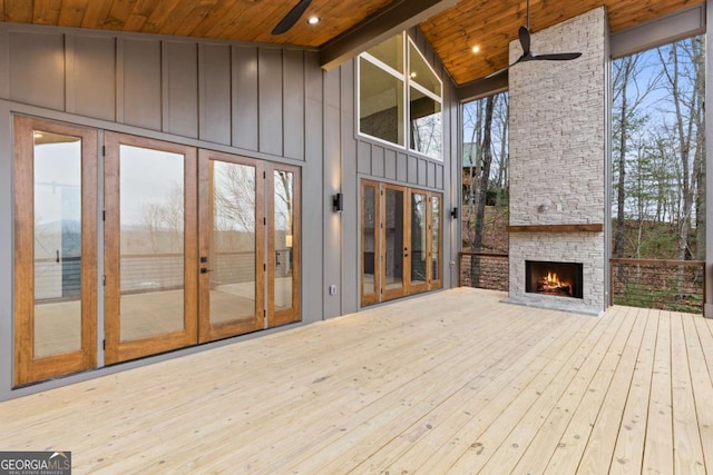 deck with ceiling fan, an outdoor stone fireplace, and french doors