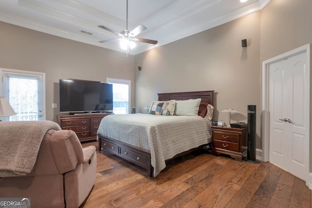 bedroom with hardwood / wood-style floors, a tray ceiling, ornamental molding, and ceiling fan