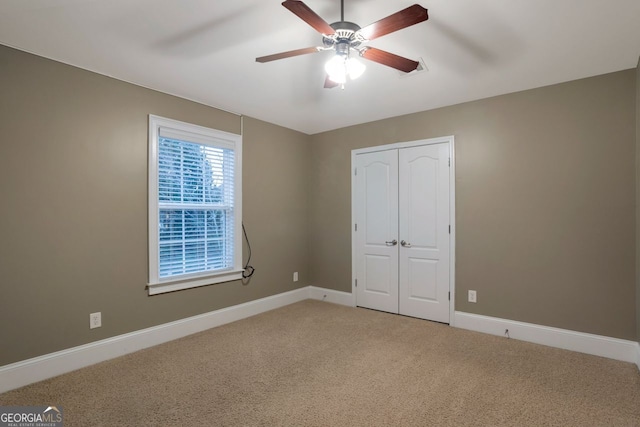 unfurnished bedroom with ceiling fan, carpet flooring, and a closet