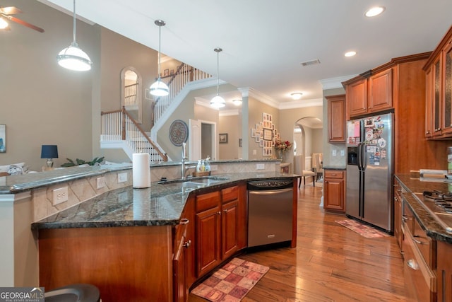 kitchen with pendant lighting, sink, light wood-type flooring, and appliances with stainless steel finishes