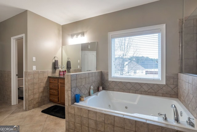 bathroom featuring tile walls, tile patterned flooring, vanity, a relaxing tiled tub, and toilet