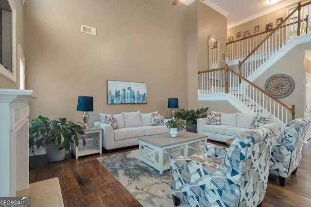 living room with dark hardwood / wood-style flooring, a towering ceiling, ornamental molding, and a premium fireplace