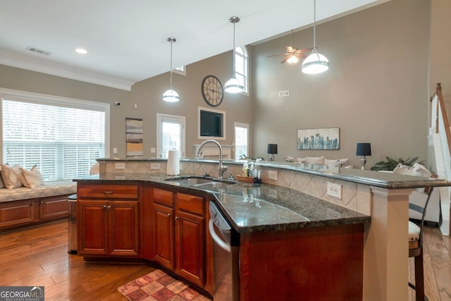 kitchen featuring stainless steel dishwasher, hanging light fixtures, sink, and a center island with sink