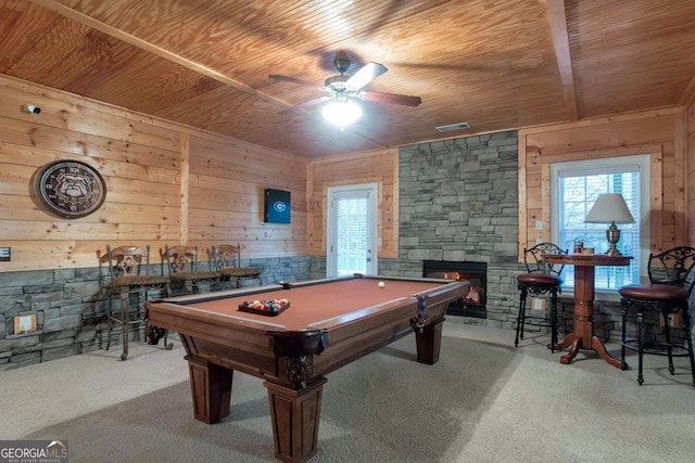 recreation room featuring a stone fireplace, light colored carpet, a wealth of natural light, and wooden ceiling