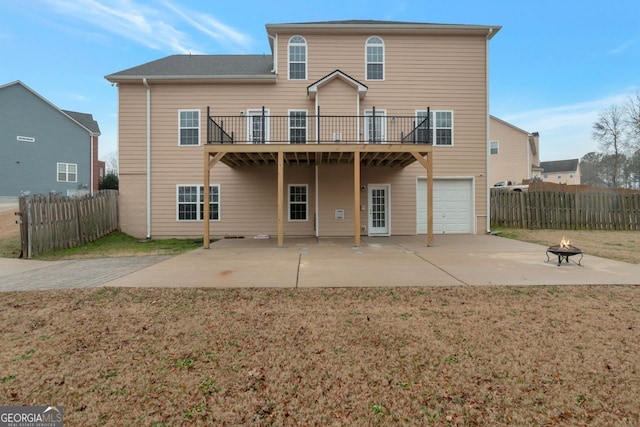 rear view of house featuring a garage, a patio, a yard, and a fire pit