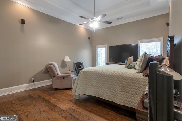 bedroom featuring dark hardwood / wood-style flooring, multiple windows, ornamental molding, and a raised ceiling