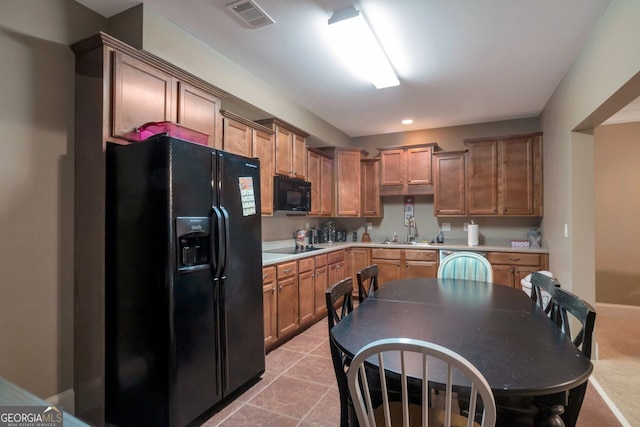 kitchen featuring sink, light tile patterned floors, and black appliances