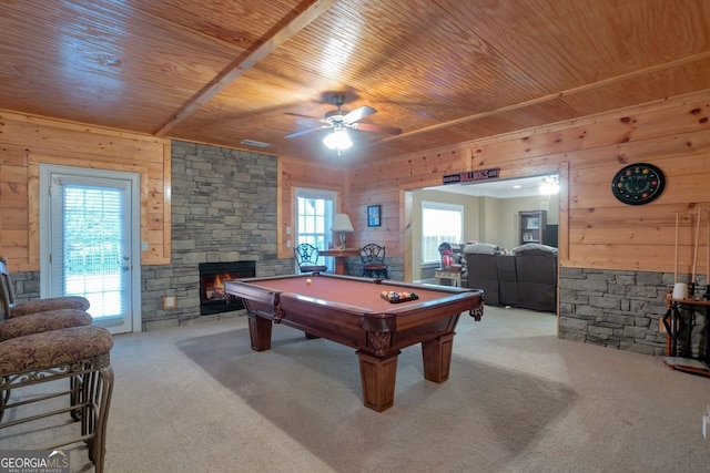 playroom with a stone fireplace, wooden walls, light carpet, and wood ceiling