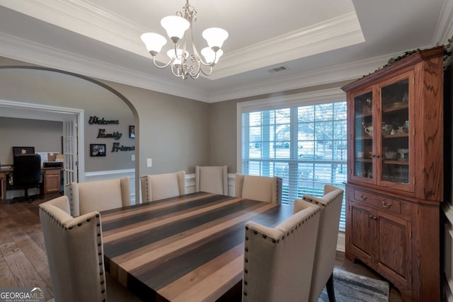 dining room with dark hardwood / wood-style flooring, ornamental molding, a raised ceiling, and an inviting chandelier