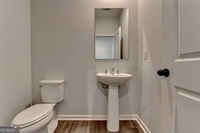 bathroom featuring wood-type flooring and toilet