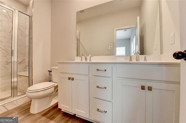 bathroom with vanity, toilet, hardwood / wood-style floors, and a shower with shower door