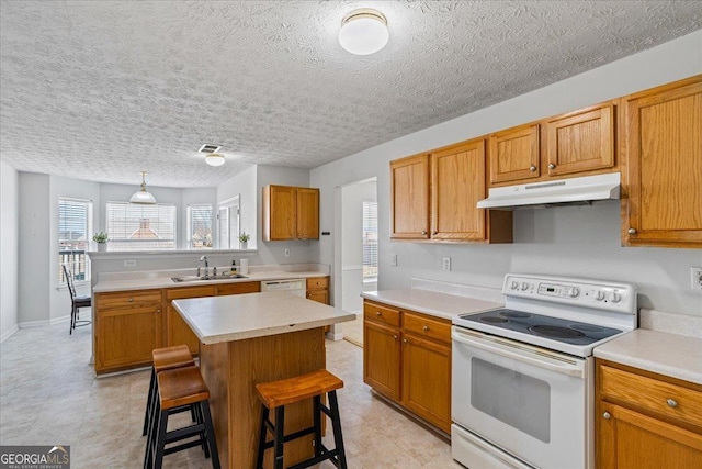 kitchen with sink, white appliances, a breakfast bar, hanging light fixtures, and a center island