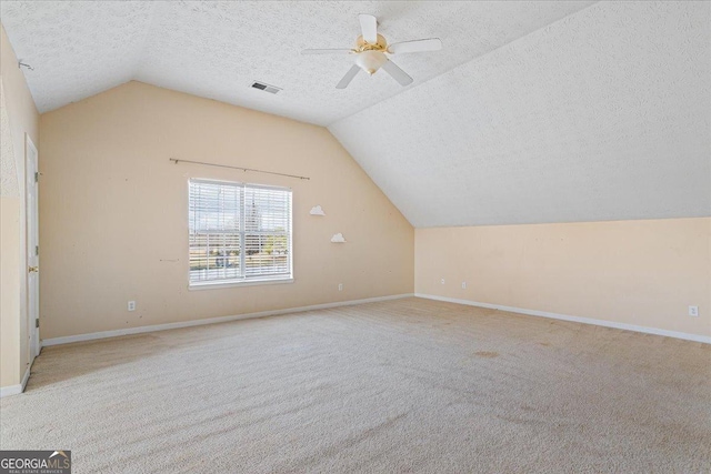 additional living space with lofted ceiling, light carpet, and a textured ceiling