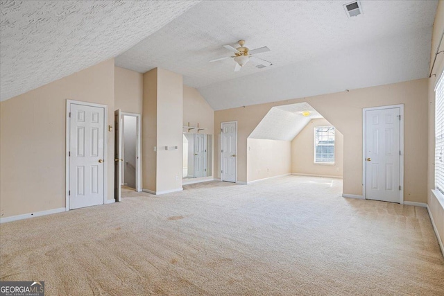 additional living space featuring lofted ceiling, ceiling fan, light colored carpet, and a textured ceiling