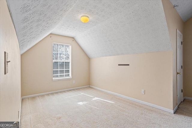 additional living space with vaulted ceiling, light carpet, and a textured ceiling