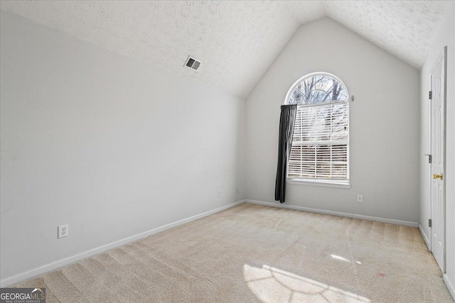 spare room with lofted ceiling, light carpet, and a textured ceiling