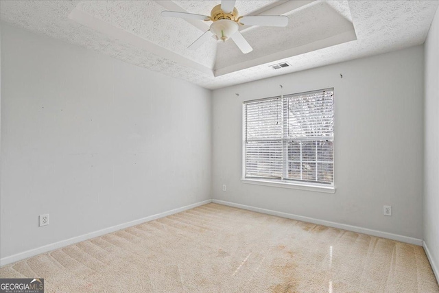 carpeted empty room featuring ceiling fan, a tray ceiling, and a textured ceiling